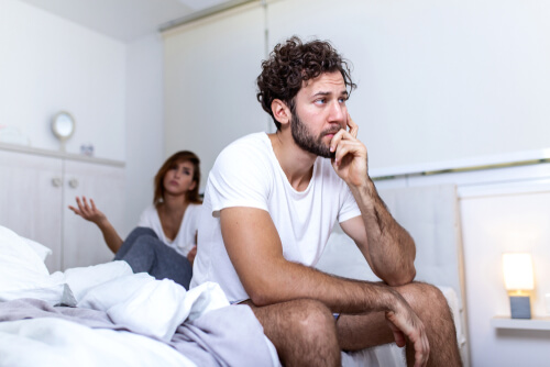 disgruntled man sitting on edge of bed