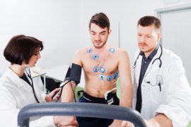 Man on a treadmill having blood pressure and vitals taken.